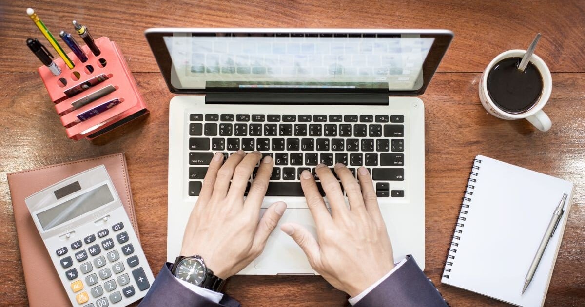 Business valuation professional using a laptop and calculator to review financial information.
